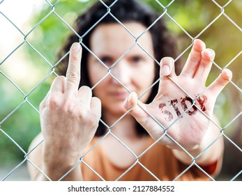 Woman with serious face behind a fence repressing someone,with the word stop written on the other hand.Concept of feminism, demand for equality and end to violence. Concept of stop the war.