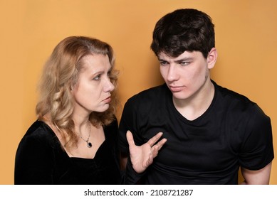 A Woman With A Serious Face Criticizes Her Teenage Son, The Boy Humbly Listens To His Mother With Patience. Portrait Of A Teenage Boy And His Mother, They Communicate. The Concept Of Upbringing