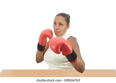 Woman serious looking at camera wearing red boxing gloves sitting at desk isolated on white background - Powered by Shutterstock