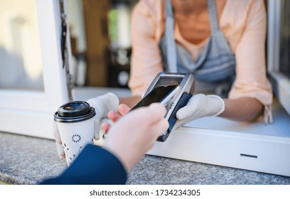 Woman serving coffee through window, contactless payment and back to normal concept.