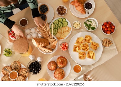 Woman serving food on table indoors, top view. Luxury brunch