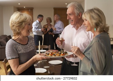 Woman Serving Hors D'oeuvres To Her Guests At A Dinner Party