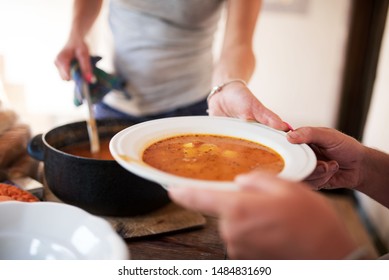 Woman Serving Plate Of Soup To Men