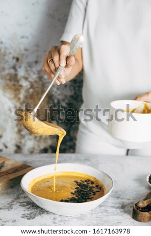 A woman serving pumpkin soup in a bowl

