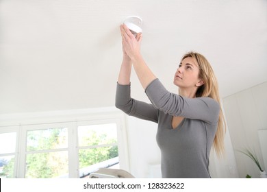 Woman Setting Up Fire Alarm Inside House
