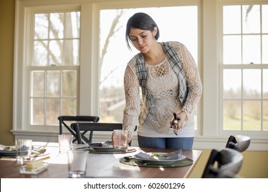 A woman setting the table for a meal - Shutterstock ID 602601296