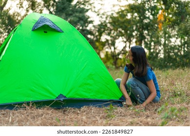 Woman setting up tent at camp site.
