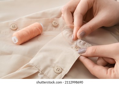 Woman Sewing Button On Shirt Sleeve, Closeup