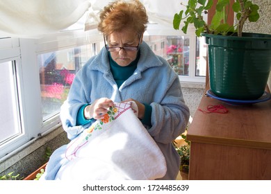 Woman Sewing Cross Stitch A Tablecloth Sitting At Home