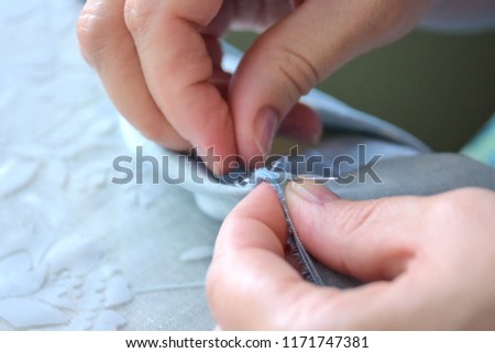 Woman sewing hands with needle and blue thread