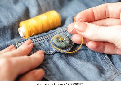 Woman Sewing on button. Thread needle Sewing Button Jeans. Close-up. Authentic Lifestyle. Hand made