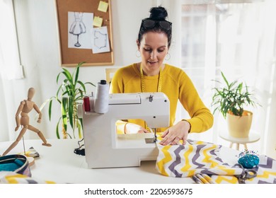 Woman sewing on a sewing machine at her home. Woman seamstress work on the sewing-machine