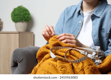 Woman sewing sweater with needle at home, closeup - Powered by Shutterstock