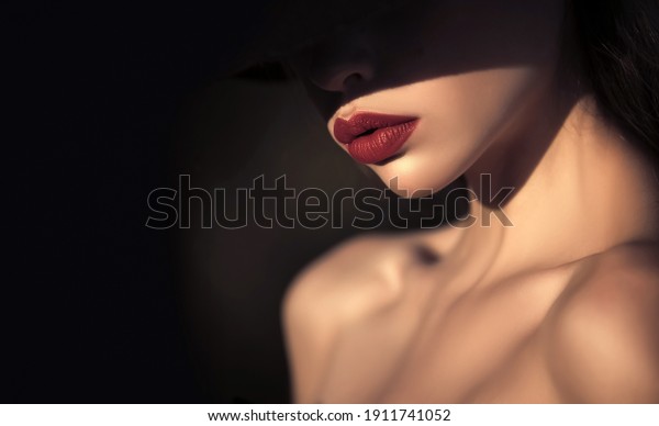 Woman in\
shadows. Elegant woman with red lips. elegant woman with naked\
shoulders on black background, copy\
space