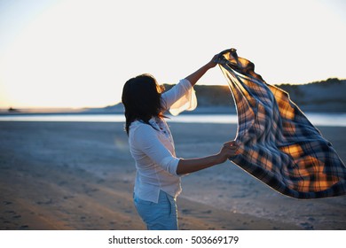 Woman Shaking Blanket On Beach At Sunset, Cannon Beach, California, USA