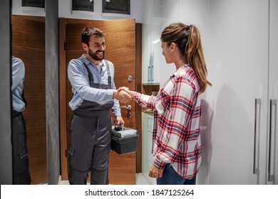 Woman shaking hands with a repairman while standing at home.
