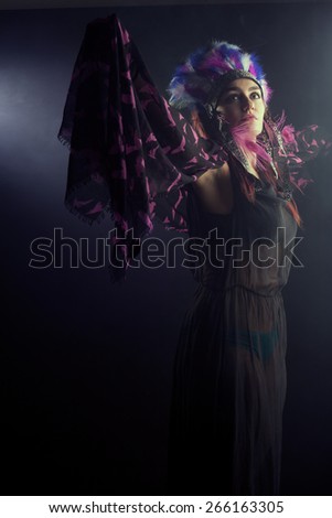 woman shaman or brasilian dancers in the smoke on black backgroung puts on his gods