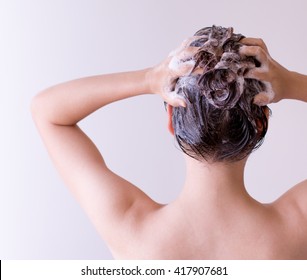 Woman Shampooing Her Hair With Both Hands On Her Head In Front Of A White Background.