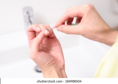 Woman shaping and cleaning her cuticles on her fingernails in a health care, skincare and beauty concept using a sharp tool