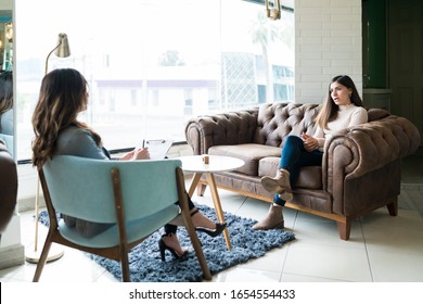 Woman Sharing Problems With Female Therapist While Sitting On Couch At Office