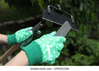 Woman sharpening hoe outdoors, closeup. Gardening tools - Powered by Shutterstock