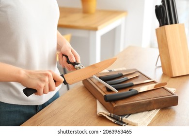 Woman sharpening knife in kitchen, closeup