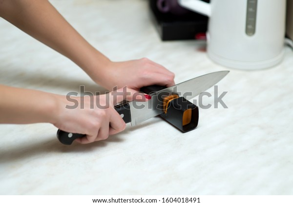 woman sharpening a knife with a special knife\
sharpener, close up