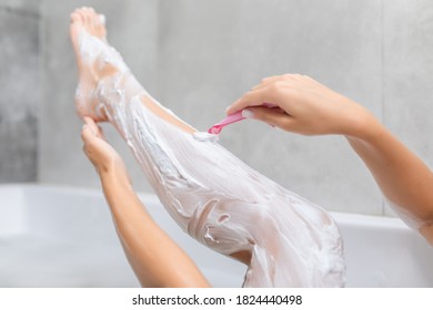Frau rasiert sich ihr Bein mit Rasierapparat im Badezimmer.