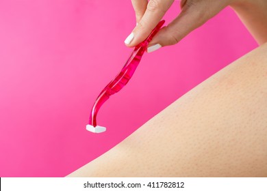woman shaving her leg with red shaver