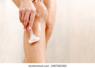 Woman shaving legs using safety razor in bathtub, enjoying depilation routine taking bath in modern bathroom at home. Hair removal and bodycare cosmetics concept - Powered by Shutterstock