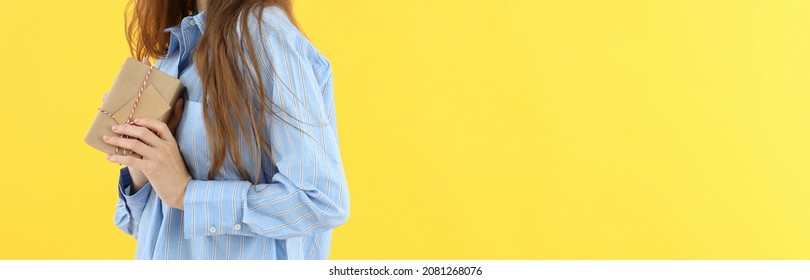 Woman in shirt holds gift box on yellow background - Shutterstock ID 2081268076
