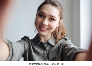 Woman in shirt making selfie. gray background