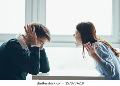 A Woman In A Shirt Screams To A Man And A Partner Holds Hands Near His Ears