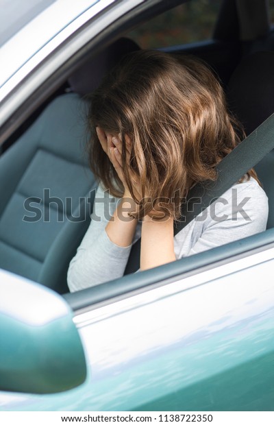 A woman in shock is holding her head in the\
car. The concept of road\
accidents.