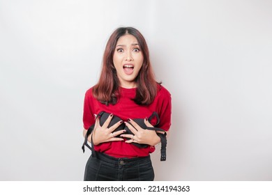 A woman is shocked while holding a bra against a white background. Concept of Breast cancer awareness and international no bra day celebration