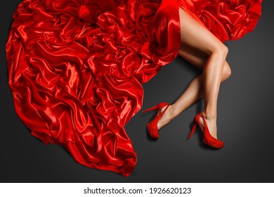 Woman Shoe High Heels Fashion. Model in Red Shoe Red Skirt Dress lying over Silk Fabric on Black Background Floor