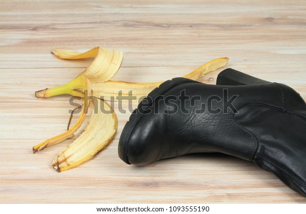 Woman shoe to slip on a banana peel. Fall on a\
banana skin on wooden\
board