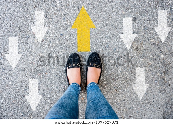 woman shoes on asphalt and opposing direction arrows\
on asphalt ground, personal perspective footsie concept for finding\
your own way \
