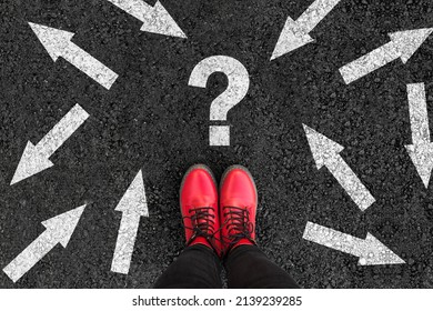 woman in shoes standing on asphalt next to multitude of arrows in different directions and question mark, confusion choice chaos concept 