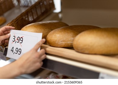 Woman shop assistant changing prices of bread in supermarket, the concept of increasing inflation - Shutterstock ID 2153609365