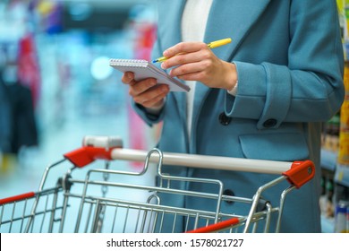 Woman Shopper With Cart In The Store Aisle With Grocery List During Shopping Food 