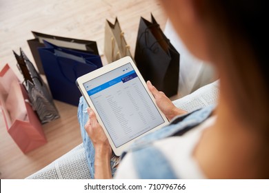 Woman With Shopping Bags Checks Bank Statement On Digital Tablet