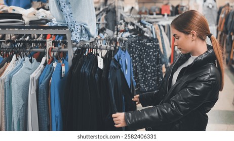 Woman shopping, browsing clothing rack, selecting stylish apparel in modern retail environment, making fashion choices