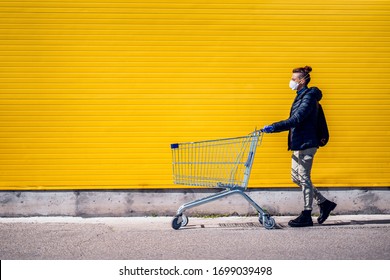 Woman With A Shopping Cart In Front Of A Store, Wearing A Mask During A Coronavirus Pandemic / Covid-19.