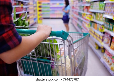 Woman with shopping cart purchasing food in a supermarket. - Shutterstock ID 794478787