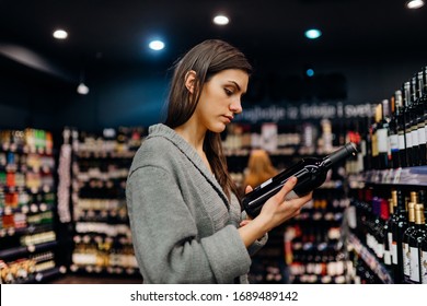 Woman Shopping For Expensive Wine In Supermarket Alcohol Store.Choosing And Buying Good Cheap Wine.Benefits Of Drinking Wine.Resveratrol.Everyday Binge Drinking.Oenology.Mediterranean Diet.Alcoholism