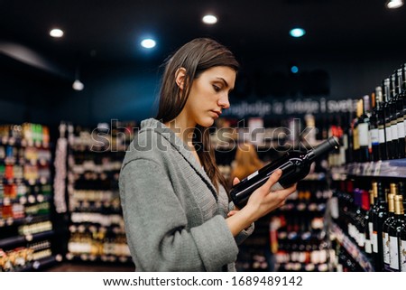 Woman shopping for expensive wine in supermarket alcohol store.Choosing and buying good cheap wine.Benefits of drinking wine.Resveratrol.Everyday binge drinking.Oenology.Mediterranean diet.Alcoholism Сток-фото © 