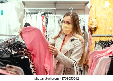 Woman Shopping In Fashion Store Wearing Face Mask Looking At Some Clothes