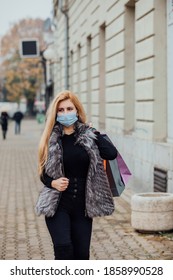 Woman In Shopping. Happy Woman With Shopping Bags Enjoying Shopping. The Woman Is Wearing A Facemask To Prevent Corona Virus. 