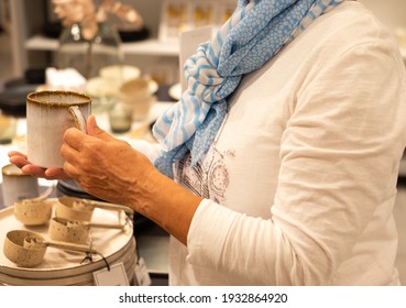 Woman Shopping In A Home Improvement Store, Holds A Cup In Her Hand